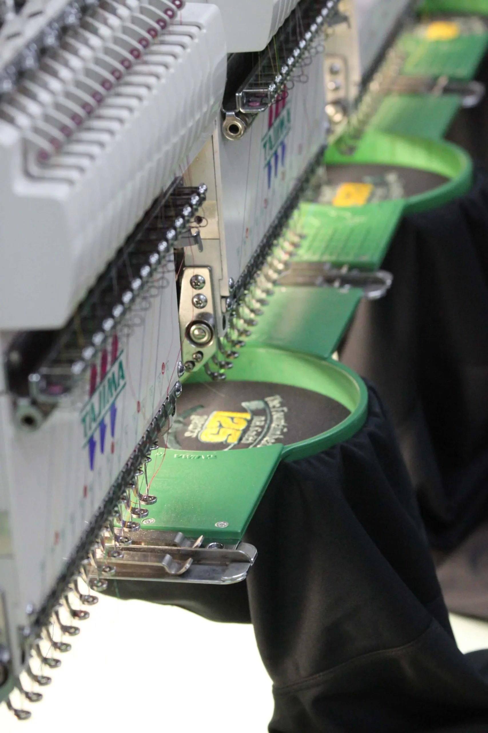 Close-up of a multi-head Tajima embroidery machine stitching a logo