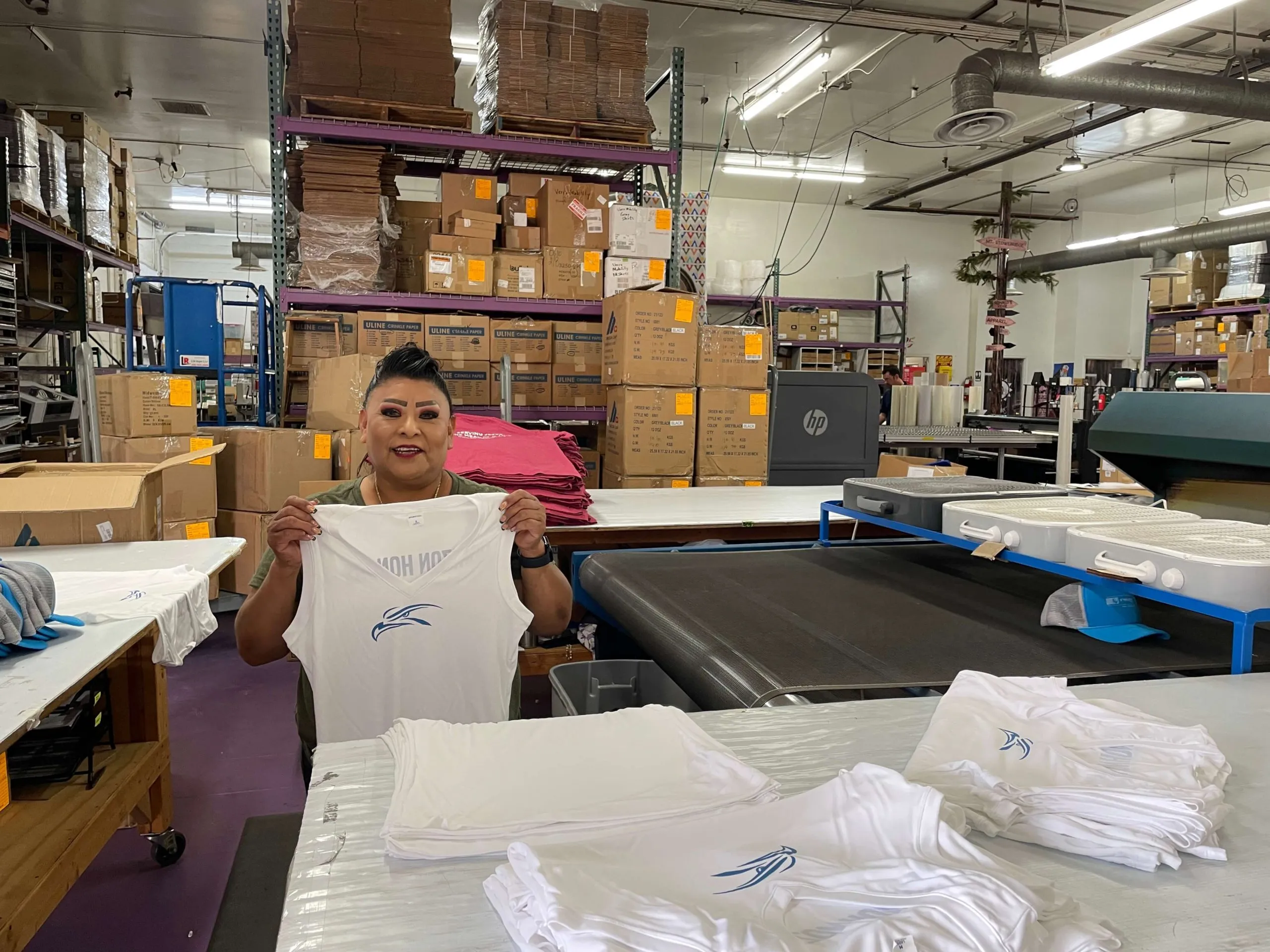 EZ Print Source team member holding a finished folded garment in the production warehouse